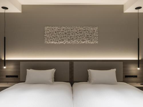 two beds sitting next to each other in a bedroom at HOTEL FORZA SAPPORO STATION in Sapporo