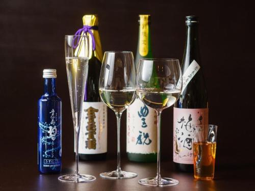 three glasses of white wine next to bottles of wine at NIPPONIA HOTEL NARA NARAMACHI in Nara