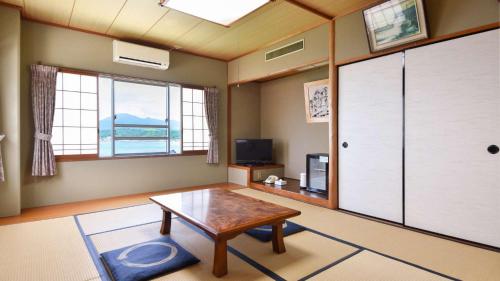 a living room with a table and a window at Marine Hotel Harimo in Hamada