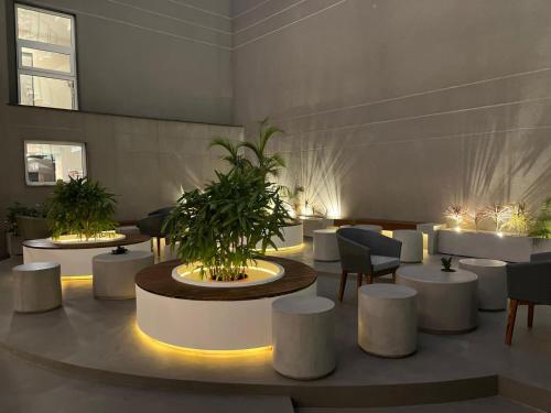a lobby with white tables and chairs and plants at AIR by Ahuja Residences in Gurgaon