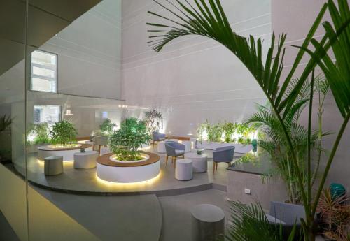 a large room with tables and chairs and plants at AIR by Ahuja Residences in Gurgaon