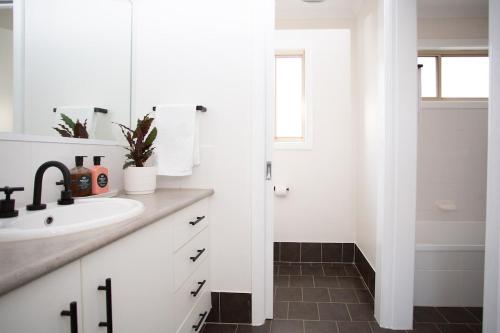 a white bathroom with a sink and a shower at Jillamatong House in Moonbah