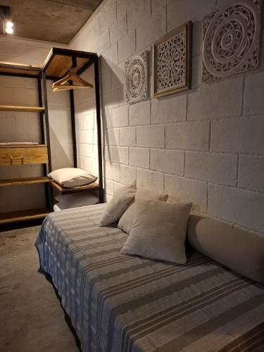 a bed in a room with a brick wall at Kot Nou - Kwizine Mama Manze Lakaz in Mahébourg