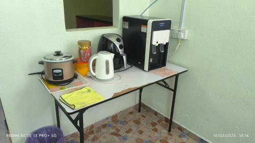 a table with a coffee maker and a coffeemaker on it at Tiffana Homestay in Kampong Ayer Terjun