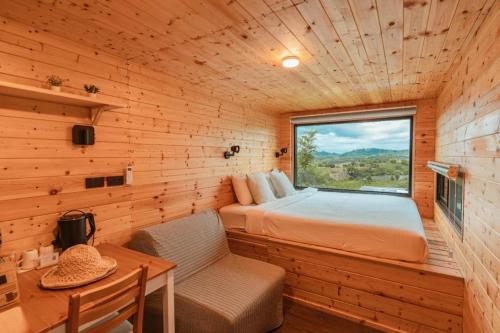 1 dormitorio en una cabaña de madera con cama y ventana en THUNWA the CAMPSITE, en Khao Kho