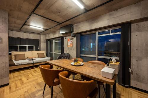 a dining room with a table and chairs and a couch at Base605 in Kurume