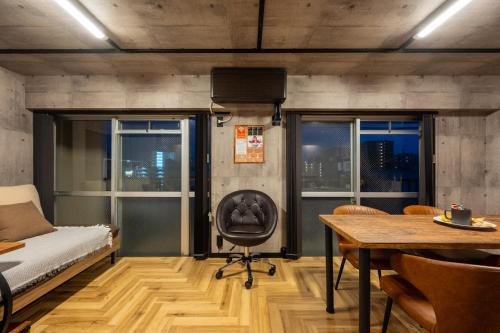 a room with a bed and a chair and a table at Base605 in Kurume