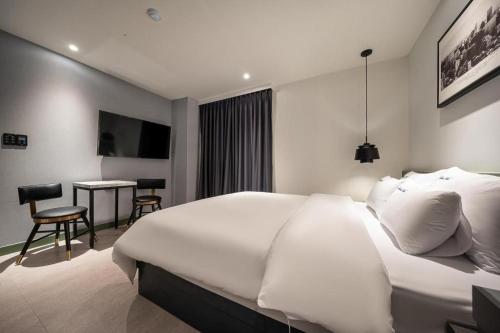 a bedroom with a large white bed and a desk at Wonju Bellino Hotel in Wonju