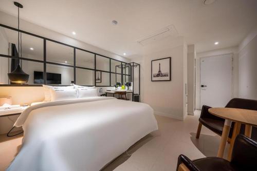 a bedroom with a large white bed and a table at Wonju Bellino Hotel in Wonju