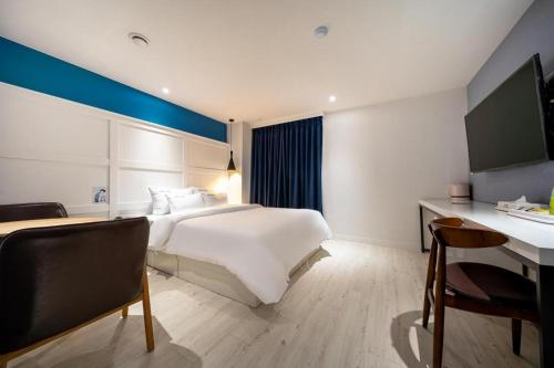 a hotel room with a large bed and a desk at Wonju Bellino Hotel in Wonju