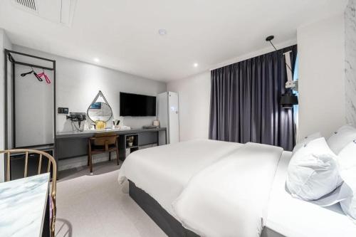 a hotel room with a white bed and a desk at Wonju Bellino Hotel in Wonju