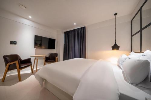 a white bedroom with a large bed and a table at Wonju Bellino Hotel in Wonju