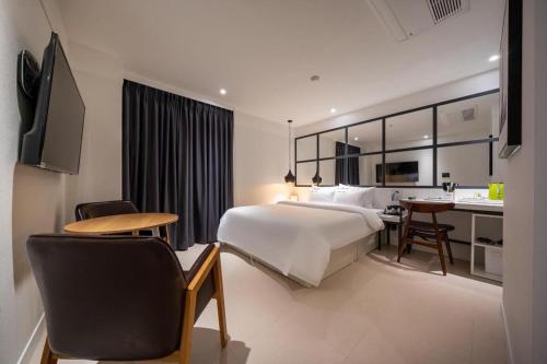 a hotel room with a bed and a desk and a kitchen at Wonju Bellino Hotel in Wonju
