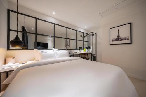 a bedroom with a large white bed and a desk at Wonju Bellino Hotel in Wonju