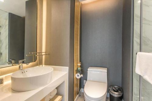 a bathroom with a white sink and a toilet at Magnotel Hotel Suzhou Shiquan Street Wangshiyuan in Suzhou
