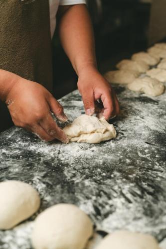 a person kneading a piece of dough on a table at Casa Olivea in Valle de Guadalupe
