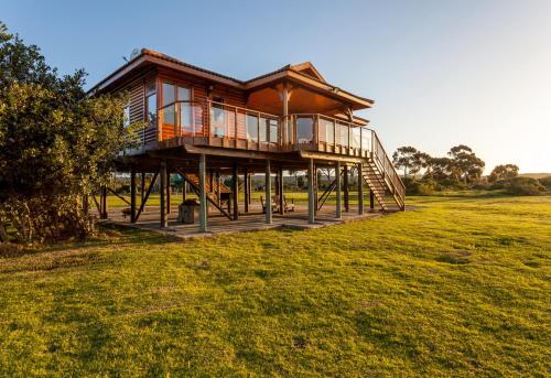a large wooden house on posts in a field at Rivers End Farm Stanford with solar energy in Stanford