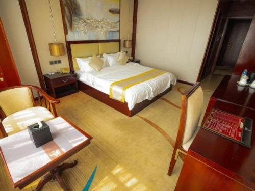 a bedroom with a bed and a table and a desk at Grand Szechuan Hotel Vientiane in Vientiane