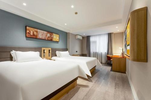 Jinjiang Inn Wuhan Wansongyuan Food Street Qushui Building في ووهان: غرفة فندقية بسريرين ومكتب