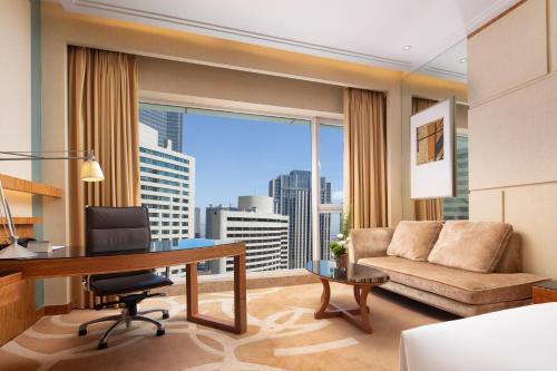 a living room with a desk and a couch at New World Dalian Hotel in Dalian