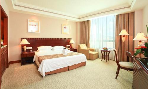a hotel room with a large bed and a chair at Sanya Baohong Hotel in Sanya