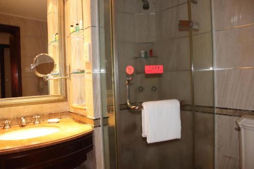 a bathroom with a sink and a shower with a mirror at Sanya Baohong Hotel in Sanya