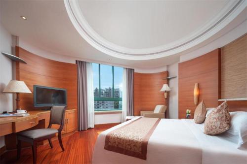 a hotel room with a bed and a desk and a computer at Sanya Baohong Hotel in Sanya