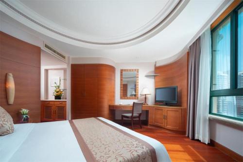 a bedroom with a bed and a desk and a television at Sanya Baohong Hotel in Sanya