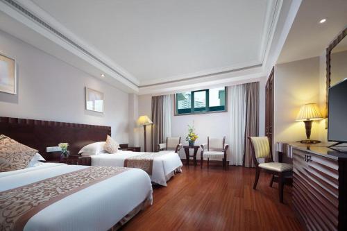 a hotel room with two beds and a television at Sanya Baohong Hotel in Sanya