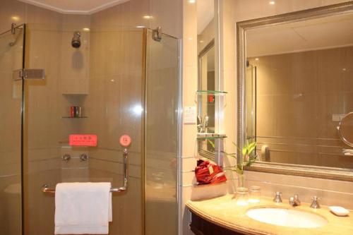 a bathroom with a shower and a sink and a mirror at Sanya Baohong Hotel in Sanya