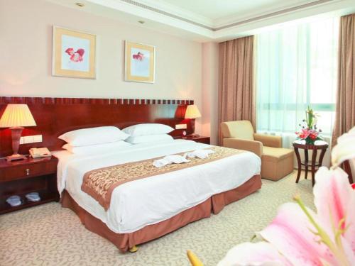 a hotel room with a large bed and a chair at Sanya Baohong Hotel in Sanya