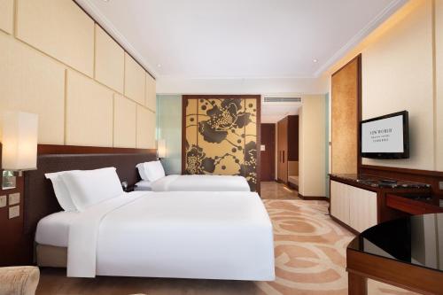 a hotel room with two beds and a flat screen tv at New World Dalian Hotel in Dalian