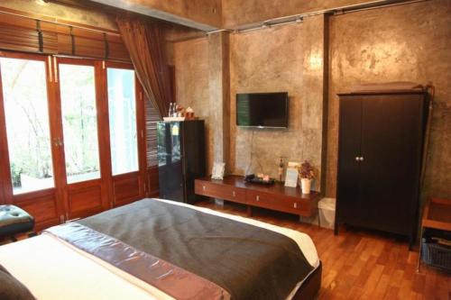 a bedroom with a bed and a tv on the wall at Baan Hmon-Oon in Chiang Mai