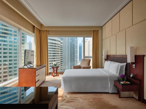 a bedroom with a large bed and a large window at New World Dalian Hotel in Dalian