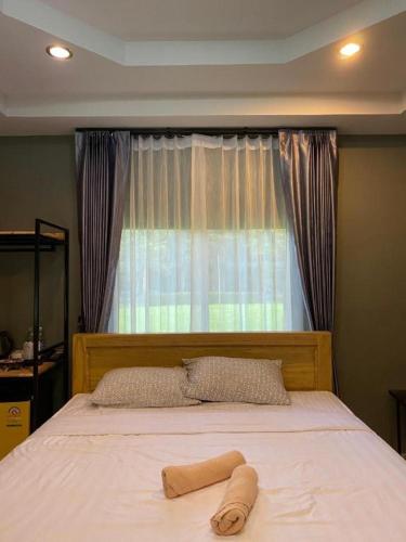 a bed in a bedroom with a large window at Ma-Kham Forest Resort in Nakhon Nayok