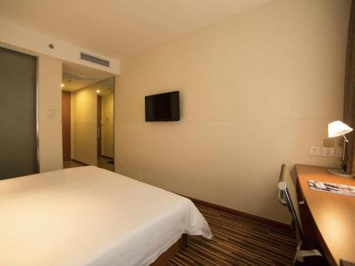 a hotel room with a bed and a tv on the wall at Jinjiang Inn Style Shenyang The Palace Huaiyuan Gate in Shenyang