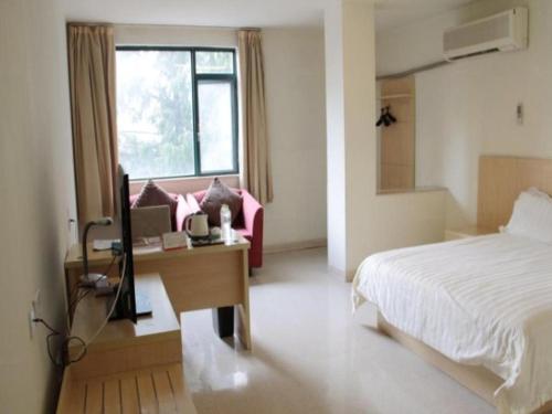 a bedroom with a bed and a desk with a television at Jinjiang Inn Nanjing Xinjiekou in Nanjing
