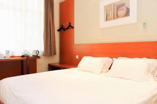 a bedroom with a white bed with a wooden headboard at Jinjiang Inn Style Shenyang The Palace Huaiyuan Gate in Shenyang