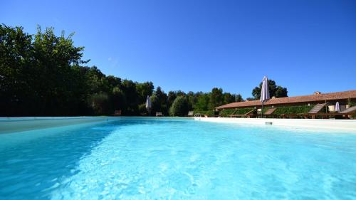 duży basen z niebieską wodą obok budynku w obiekcie Fattoria di Fugnano w mieście San Gimignano