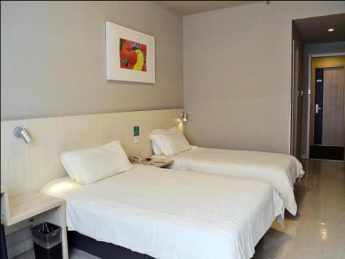 two beds in a hotel room with white sheets at Jinjiang Inn Nanjing Xinjiekou in Nanjing
