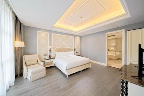 a bedroom with a white bed and a chair at Yin Run Jin Jiang Castle Hotel in Huzhou