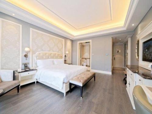 a bedroom with a large white bed and a couch at Yin Run Jin Jiang Castle Hotel in Huzhou