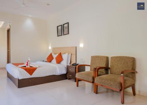 a hotel room with a bed and two chairs at Golden Landmark Green Valley Beach Resort in Dona Paula