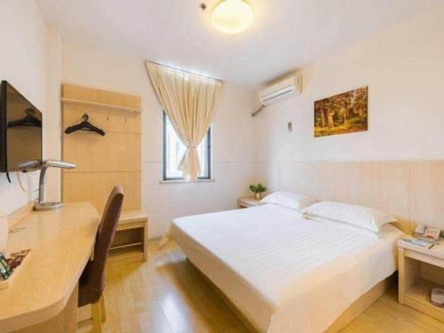 a bedroom with a white bed and a desk and a window at Magnotel Shanghai Henglong Plaza in Shanghai