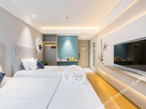 a hotel room with two beds and a tv at Magnotel Shanghai Henglong Plaza in Shanghai