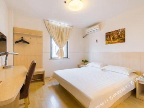 a bedroom with a bed and a desk and a window at Magnotel Shanghai Henglong Plaza in Shanghai