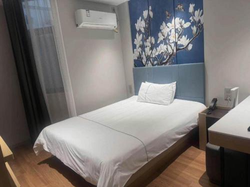 a small bed in a room with a painting on the wall at Magnotel Shanghai Henglong Plaza in Shanghai
