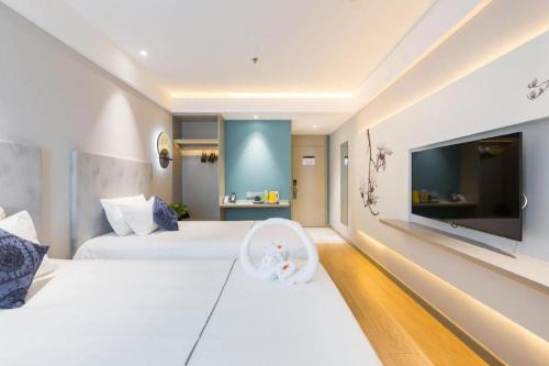 a hotel room with two beds and a flat screen tv at Magnotel Shanghai Henglong Plaza in Shanghai