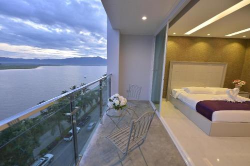 a bedroom with a balcony with a bed and a view of the water at Phuglong Hotel in Phayao