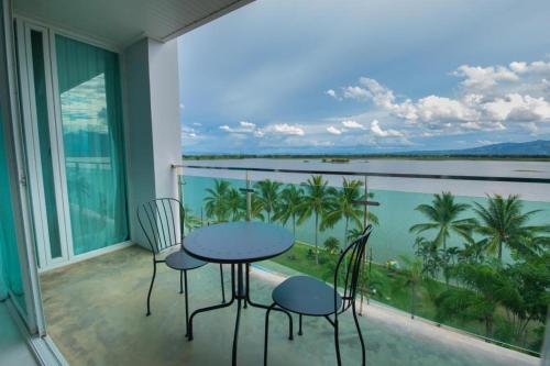 a balcony with a table and chairs and a view of the water at Phuglong Hotel in Phayao